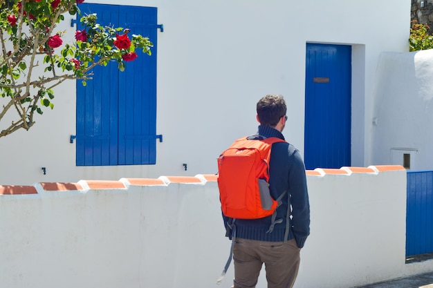 Viajero con una mochila roja cerca de la casa de belleza.