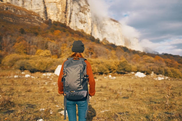 Un viajero con una mochila en un sombrero de vaqueros está caminando por las montañas de la naturaleza