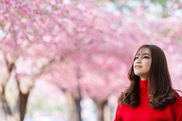 Viajero de mujer alegre mirando flores de cerezo o flor de sakura que florece en el parque