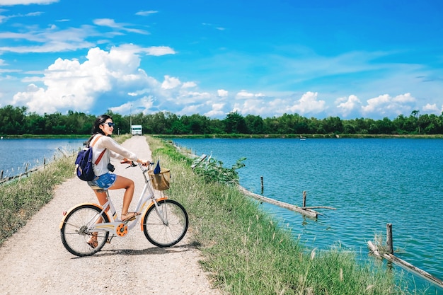 Viajero mujer andar en bicicleta y disfrutar de la vista del lago y el bosque de manglar