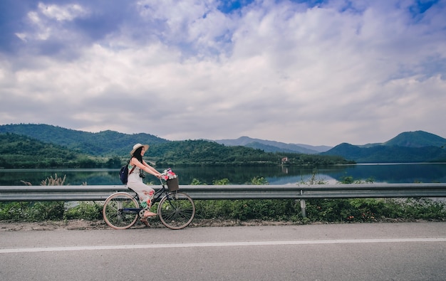 Viajero mujer andar en bicicleta y disfrutar de la vista de la naturaleza cerca del lago