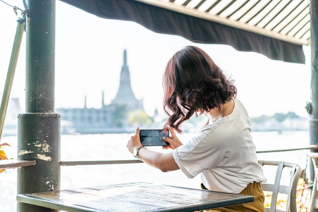 Viajero mujer asiática tomando una foto en la cafetería