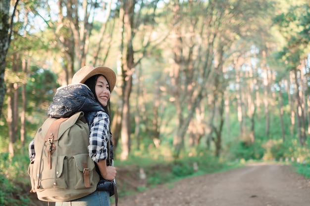 Viajero mujer joven con mochila en un bosque. Senderismo en verano.