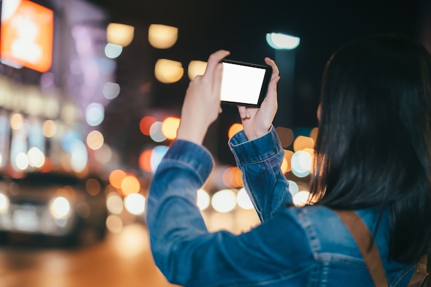 Viajero de la mujer joven que toma la foto con el teléfono móvil.