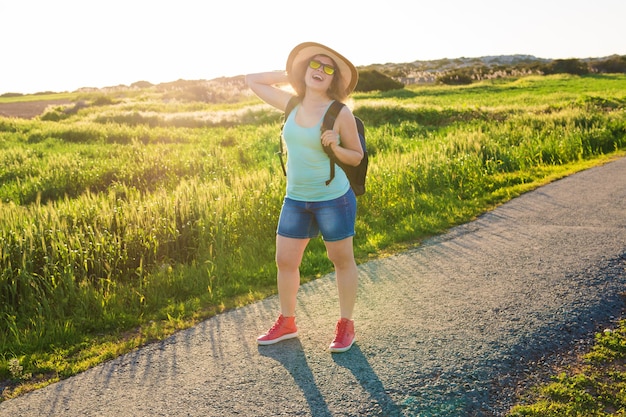 Viajero mujer mirando puesta de sol en campo verde