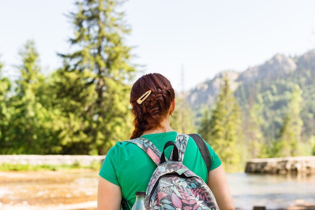 Viajero de mujer con mochila mirando montañas y bosques increíbles