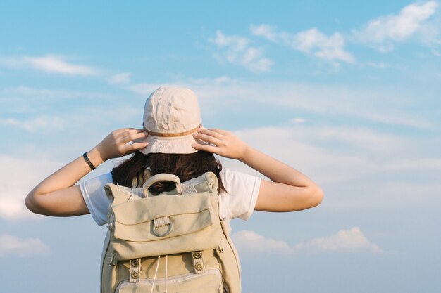 Viajero mujer con mochila con sombrero y mirando al cielo azul, concepto de viaje, espacio para texto y momento atmosférico