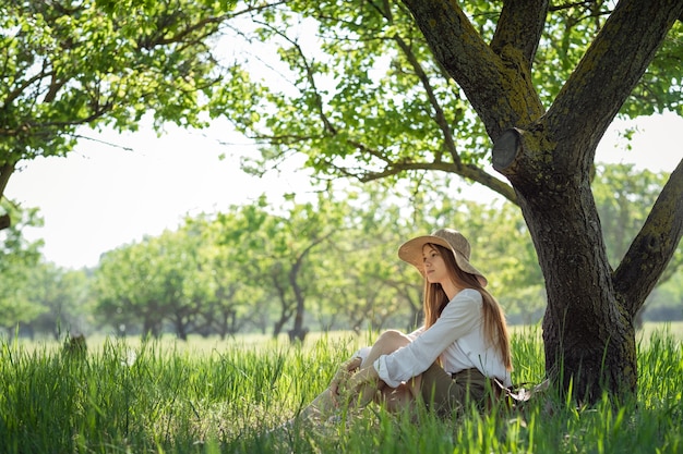 Viajero de mujer con mochila y sombrero sentado en un bosque increíble, concepto de viaje de pasión por los viajes, espacio para texto, momento atmosférico. día de la Tierra