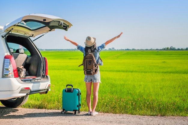 Viajero de mujer de pie cerca de un vehículo con puerta trasera durante un viaje para ir de vacaciones