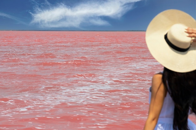 Viajero de mujer con sombrero mira increíble exótico lago salado rosa y cielo azul. concepto de viaje de pasión por los viajes, espacio para copiar texto. Enfoque selectivo. Foto de alta calidad