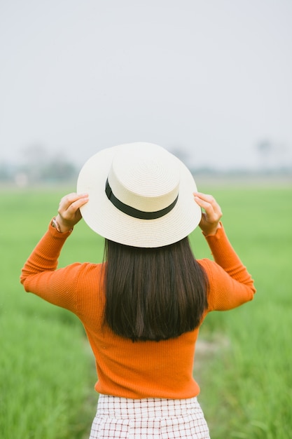 Viajero mujer sosteniendo sombrero y mirando el campo verde