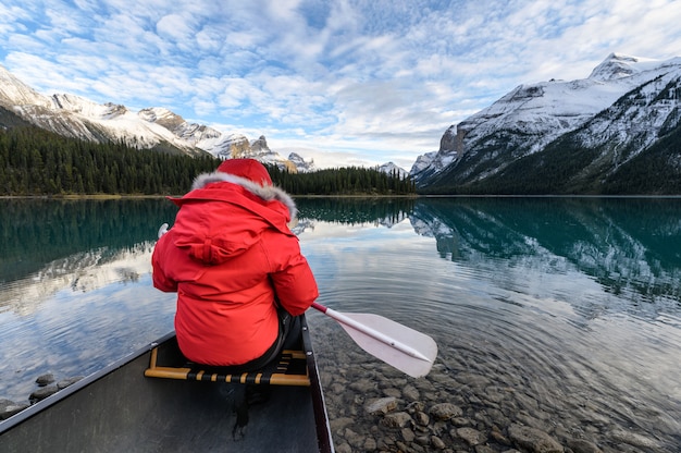 Viajero con paleta en canoa roja en el lago