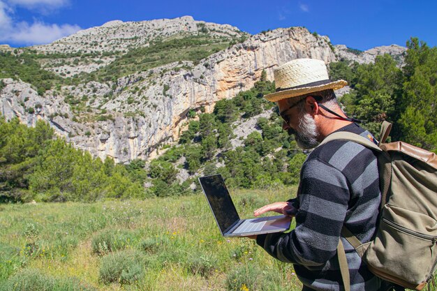 Viajero que trabaja de forma remota en una computadora netbook mientras disfruta de las vistas del paisaje natural al aire libre