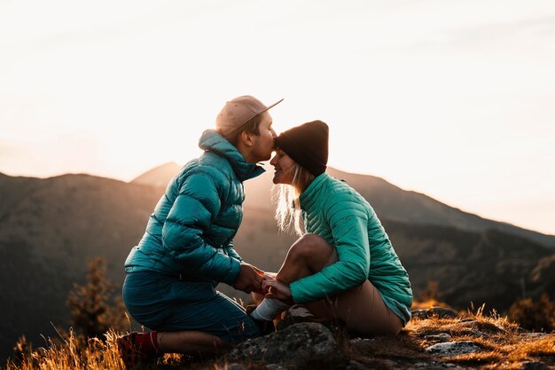 Viajero de senderismo en las montañas Paisaje soleado Viajero turístico en maqueta de vista de fondo Primer plano de una hermosa joven pareja sonriente abrazando Besos