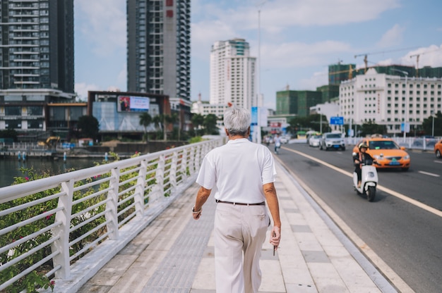 Viajero senior anciano caminando en el centro de la ciudad asiática con rascacielos. Viaje aventura naturaleza en China, destino turístico hermoso Asia, vacaciones de verano viaje viaje concepto de viaje