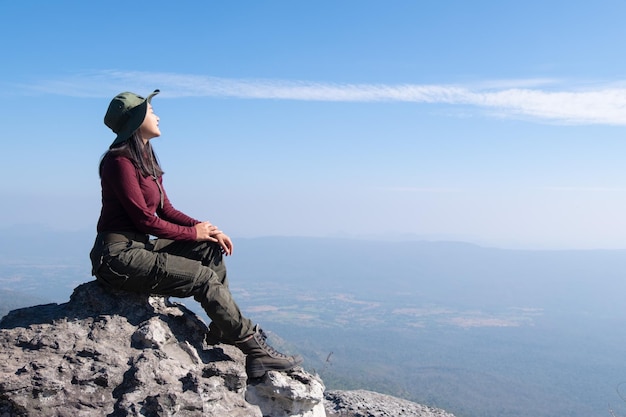 Un viajero se sienta en una roca en una montaña alta con una hermosa vista del cielo