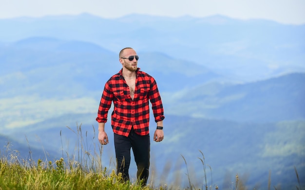 Viajero solitario hombre macho sexy en camisa a cuadros viaje aventura hipster moda vaquero en sombrero al aire libre campo concepto agricultor en rancho hombre en paisaje de montaña camping y senderismo