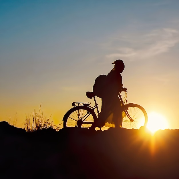 Viajero solo - mujer con bicicleta al atardecer, silueta contra el cielo oscuro