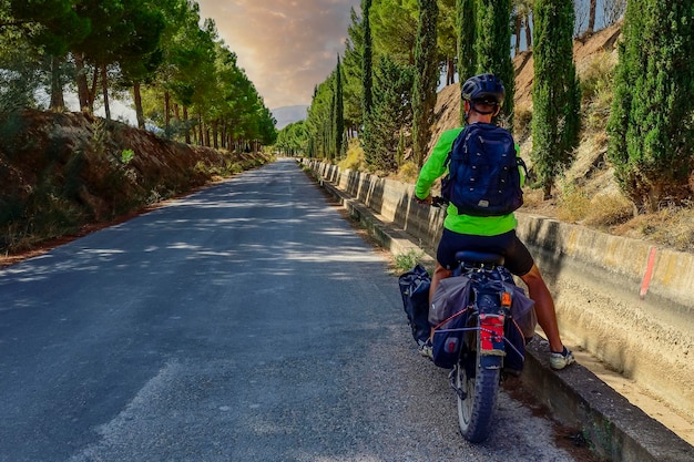 Viajero trotamundos en bicicleta contemplando el camino a seguir