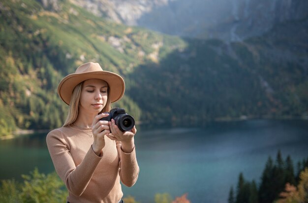 Viajero turístico fotógrafo de pie en la cima verde en la montaña