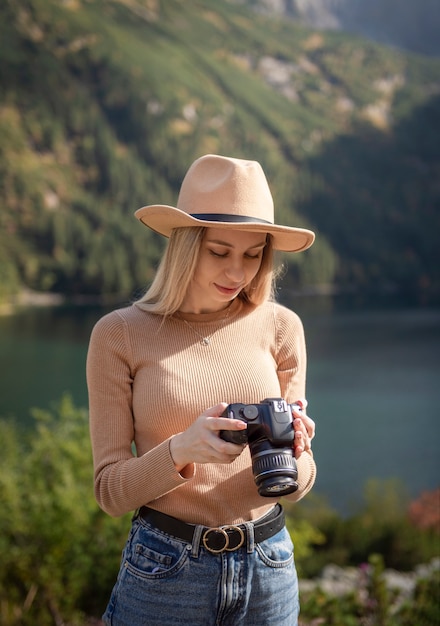 Viajero turístico fotógrafo de pie en la cima verde en la montaña