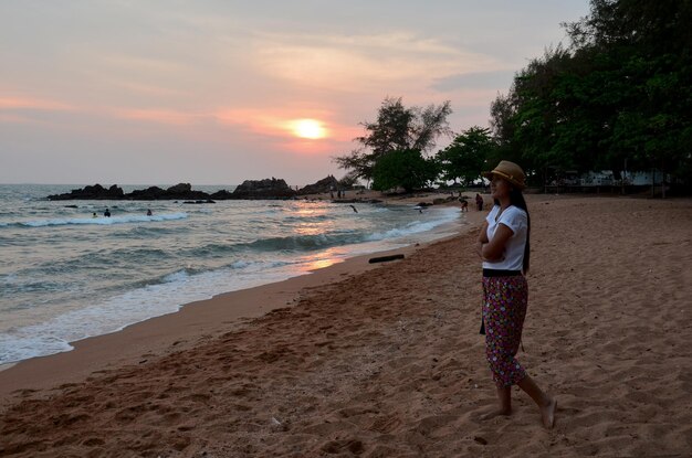 Viajeros asiáticos mujeres tailandesas viajan visitan y posan para tomar fotos con vistas al paisaje marino de la playa de arena de Kung Wiman y olas de agua en el océano al atardecer en Chanthaburi Tailandia