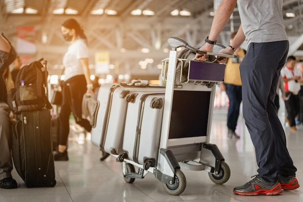 Los viajeros están caminando para arrastrar el equipaje en la moderna terminal del aeropuerto para viajar a nuevos lugares. Vista trasera. Copie el espacio. Equipaje, viajero, viajes, aeropuerto, caminar, concepto de vacaciones.