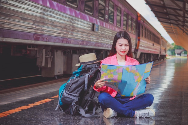 Viajeros femeninos que llevan una mochila que lleva un mapa para el viaje del tren.