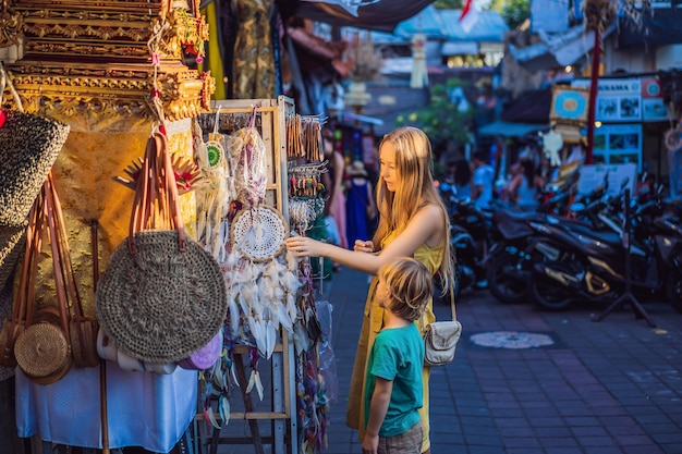 Los viajeros de mamá e hijo eligen souvenirs en el mercado de Ubud en Bali Indonesia