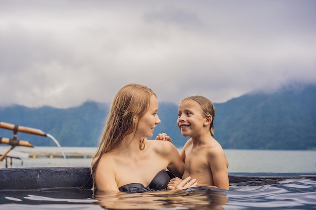 Viajeros de mamá e hijo en Hot Springs en Bali en el fondo del lago Concepto de viajar con niños