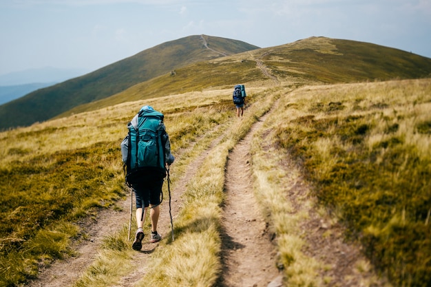 Los viajeros con mochilas pesadas caminan por las montañas