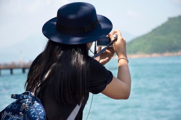 Viajeros mujer tailandesa sentada relajarse y tomar fotos con vistas al paisaje de la isla y el mar en el puerto Victoria cerca de la carretera Shing Sai en Kennedy Town en Hong Kong China
