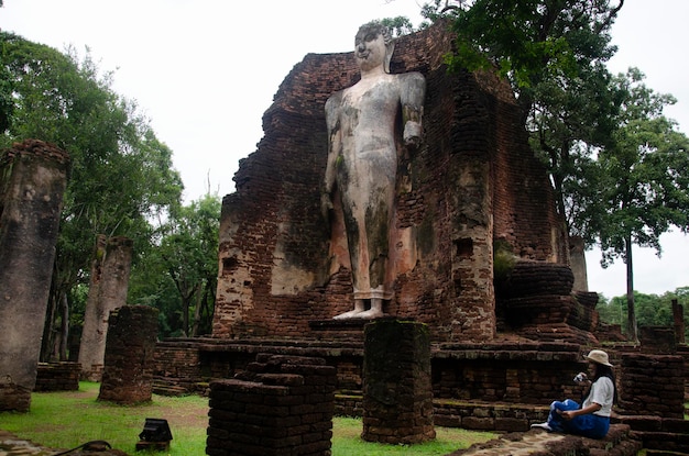 Los viajeros, una mujer tailandesa, visitan a pie y viajan, toman fotos en un edificio antiguo y las ruinas del Parque Histórico Kamphaeng Phet es un sitio arqueológico y el Área Aranyik en Kamphaeng Phet Tailandia