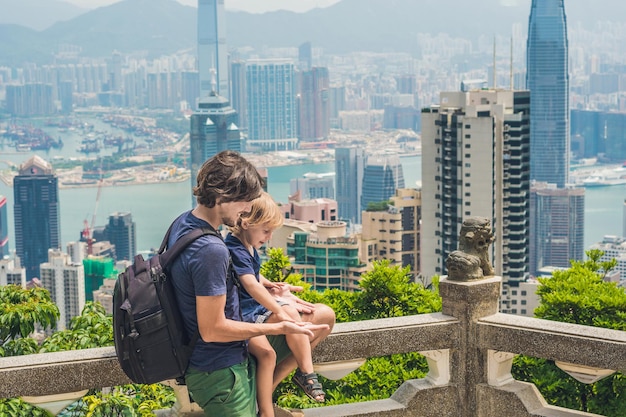 Viajeros de padre e hijo en la cima de Victoria con el telón de fondo de Hong Kong. Viajar con el concepto de niños