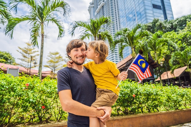 Viajeros de padre e hijo en malasia con la bandera de malasia celebrando el día de la independencia de malasia y el concepto de viaje del día de malasia a malasia