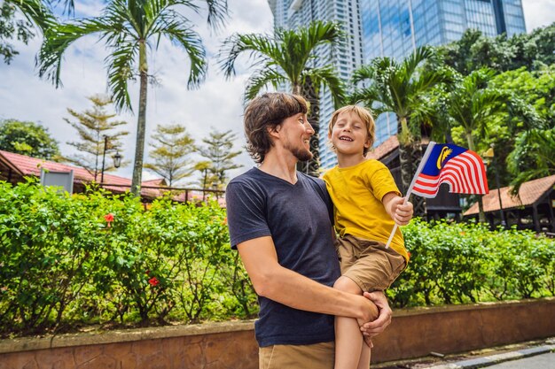 Viajeros de padre e hijo en malasia con la bandera de malasia celebrando el día de la independencia de malasia y el concepto de viaje del día de malasia a malasia