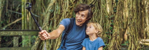 Viajeros de papá e hijo descubriendo el bosque de Ubud en el bosque de los monos, Bali, Indonesia. Concepto de viajar con niños. Videoblog, Selfie.. BANNER, formato largo