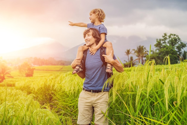 Viajeros de papá e hijo en las hermosas terrazas de arroz de Jatiluwih en el contexto de volcanes famosos en Bali, Indonesia. Concepto de viajar con niños. con la luz del sol