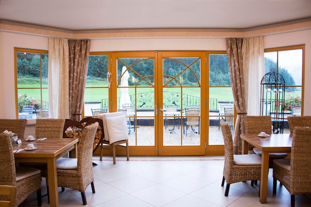 Los viajeros usan y desayunan en la cómoda sala de restaurante del hotel resort en la ciudad de Pfunds con campo de hierba y montaña por la mañana y llueve en Tirol, Austria