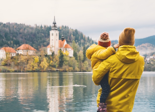 Viajes en familia Europa, madre e hijo en impermeables amarillos mirando el lago Bled en Eslovenia