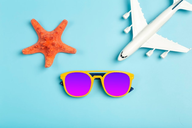 Viajes de fondo de verano. Gafas de sol, sombrero, accesorios de avión y playa sobre un fondo de color azul. Vacaciones turísticas, relajación y concepto de verano. Foto de alta calidad