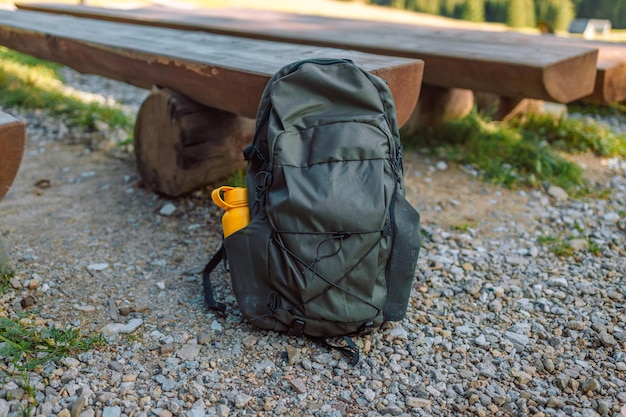 Viajes Mochila turística de color verde oliva cerca de un banco de montaña Viajes turismo y equipo de camping Picnic descanso en la naturaleza Herramientas de senderismo y senderismo activo de verano