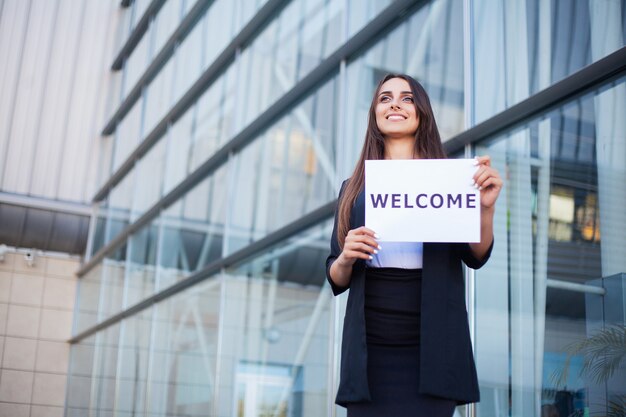 Viajes, negocios de mujeres con el cartel con mensaje de bienvenida