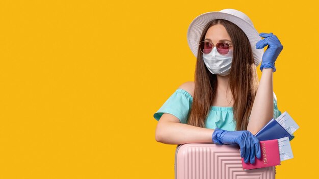 Viajes pandémicos Vacaciones de verano Mujer turista con mascarilla protectora guantes con maleta esperando vuelo aislado en espacio de copia amarilla Restricción de cuarentena COVID19 Higiene pandémica