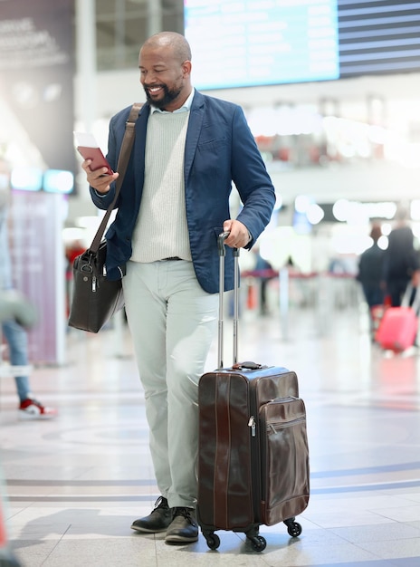 Viajes por teléfono o hombre negro feliz en el aeropuerto escribiendo chateando o haciendo contactos por correo electrónico en línea Sonrisa de avión o emocionado hombre de negocios africano leyendo noticias mientras viaja en un viaje de vacaciones