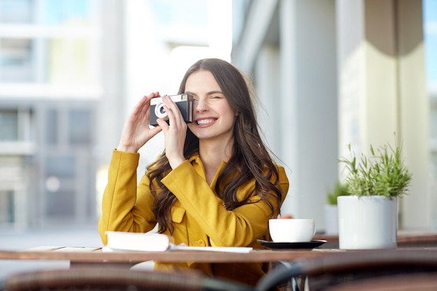 viajes, turismo, fotografía, ocio y concepto de personas - feliz joven turista o adolescente con cámara de cine y guía bebiendo cacao en la terraza del café de la calle de la ciudad