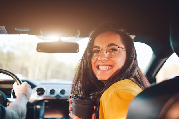 Foto viajes, turismo -hermosa mujer con un par de té o café sonriendo mientras está sentado en el asiento del coche.