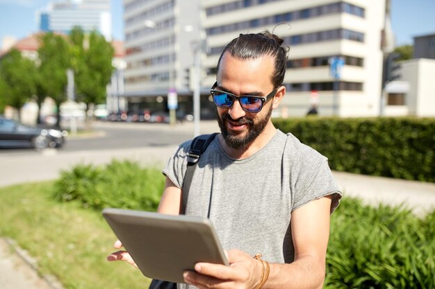 viajes, turismo, mochileros, tecnología y concepto de personas - hombre que viaja con mochila y tablet pc en la ciudad buscando ubicación