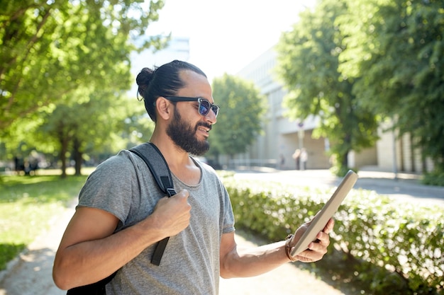 viajes, turismo, mochileros, tecnología y concepto de personas - hombre que viaja con mochila y tablet pc en la ciudad buscando ubicación