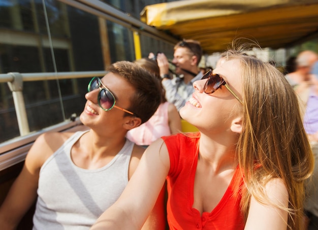 viajes, turismo, vacaciones de verano, turismo y concepto de personas - feliz pareja adolescente con gafas de sol viajando en autobús turístico